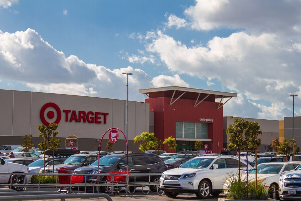 Parking lot filled with cars outside a Target store with a cloudy blue sky above.