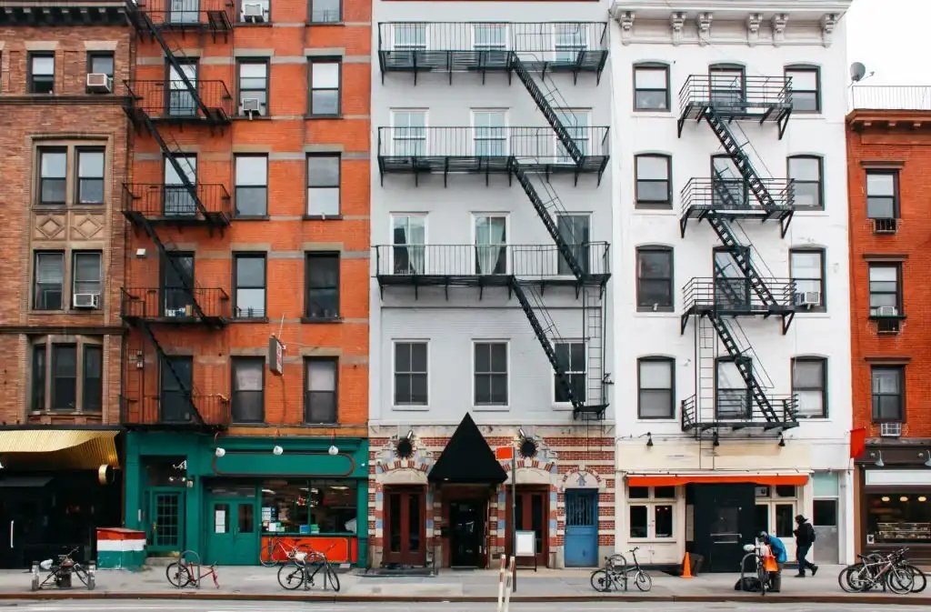 A row of diverse, colorful buildings with external fire escapes in an urban street.