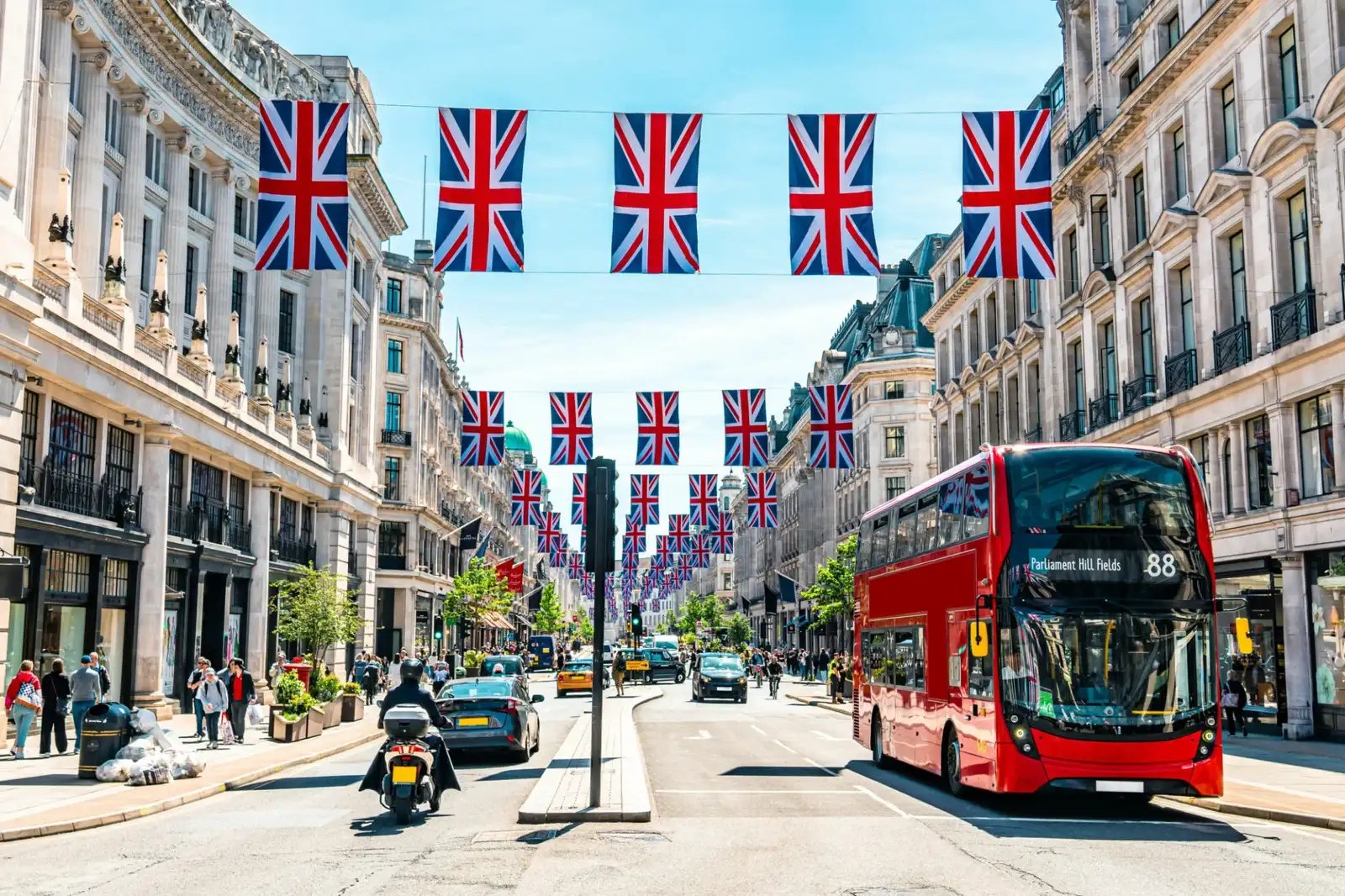 London street adorned with UK flags and a double-decker bus on a sunny day.